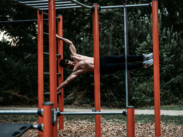 Man performing a controlled bodyweight exercise in a minimalist dark room.